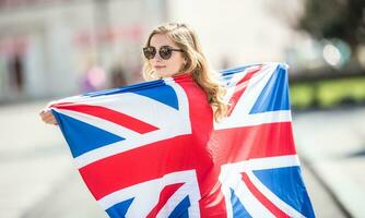 atraente feliz jovem menina com a bandeira do a ótimo Grã-Bretanha foto