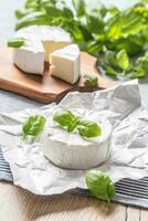 queijo Camembert ou brie queijo com manjericão folhas em mesa foto