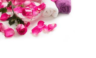 Rosa rosas pétalas dentro tigela com toalhas e puro água sobre branco.. spa e bem estar conceito foto