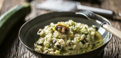 italiano risoto abobrinha cogumelos e parmesão dentro Sombrio prato foto