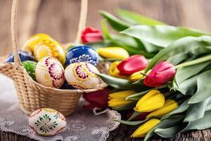 Páscoa. mão fez pintado Páscoa ovos dentro cesta e Primavera tulipas. foto