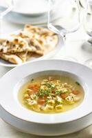 frango estoque ou sopa com legumes e pequeno italiano massa servido em uma mesa foto