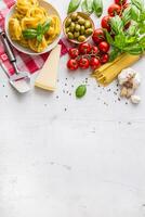 italiano Comida cozinha e ingredientes em branco concreto mesa. espaguete tagliatelle azeitonas Oliva óleo tomates parmesão queijo alho Pimenta e manjericão folhas e xadrez toalha de mesa. foto