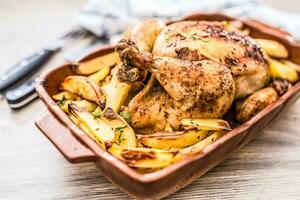 assado todo frango com batatas dentro cozimento prato. saboroso Comida às casa em a cozinha contador foto