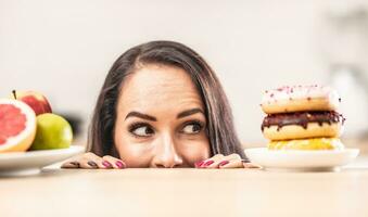 menina peeps acima a mesa olhando às prato do rosquinhas ignorando fruta em a de outros lado foto