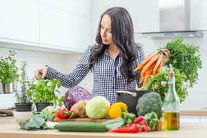 brincalhão jovem mulher dentro dela cozinha segurando fresco cenoura dentro ambos mãos - dieta vegetal e heath conceito foto