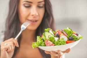 atraente jovem e feliz mulher comendo vegetal salada foto