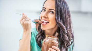 jovem lindo mulher goza emocionalmente chocolate ou avelãs creme foto