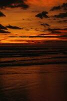 surpreendente brilhante laranja pôr do sol em a indiano oceano com ondas em bali ilha. tarde luz solar, fogo céu foto