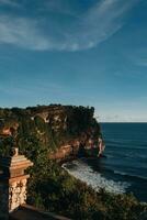 surpreendente Visão do a bali ilha com brilhante azul céu, branco nuvens, oceano, Rocha penhasco. horário de verão, viagem destino. vertical foto