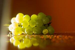 grupo do verde uvas em de madeira plinto isolado luz a partir de atrás, laranja fundo. seletivo foco foto