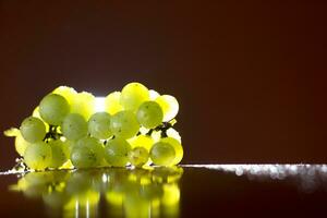 grupo do verde uvas em de madeira plinto isolado luz a partir de atrás, laranja fundo. negativo espaço foto