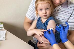 uma menina com seu pai no consultório médico da clínica está sendo vacinada contra o coronavírus