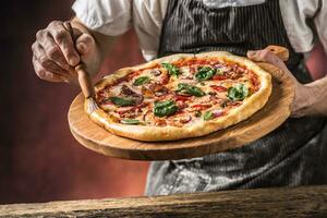 pizza e chefe de cozinha. chefe de cozinha dentro a restaurante prepara uma pizza e decora isto com Oliva óleo foto