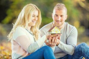 jovem amoroso casal segurando pequeno modelo casa. foto