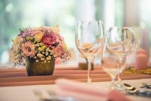Casamento mesa contexto. lindo mesa conjunto com flores e vidro copos para alguns festivo evento, festa ou Casamento recepção foto