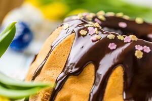 delicioso feriado eslovaco e tcheco bolo babovka com chocolate Esmalte. Páscoa decorações - Primavera tulipas e ovos foto