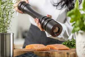 clássico de madeira Preto Pimenta moedor usava de uma chefe de cozinha para estação filetes do salmão foto