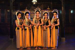 uma grupo do javanese dançarinos em pé com seus amigos enquanto vestindo amarelo fantasias e xales foto