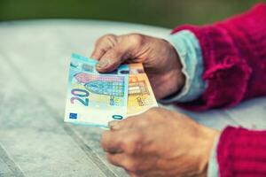 pensionista homem segurando dentro mãos euro notas foto