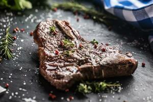 carne t-bone bife com sal Pimenta e alecrim em ardósia prato foto