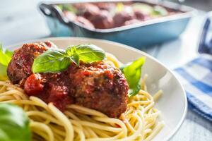 delicioso italiano refeição carne carne bolas com massa espaguete e manjericão dentro branco placa. foto