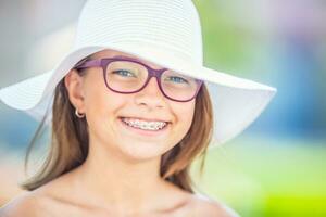 feliz sorridente menina com dental suspensórios e óculos. ortodontista e dentista conceito foto