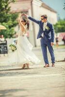 uma noivo dançando com dela noiva dentro a Cidade depois de uma casamento. ainda vestindo lindo vestes e segurando uma ramalhete fez do branco flores foto