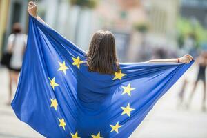 fofa feliz jovem menina com a bandeira do a europeu União dentro a ruas em algum lugar dentro Europa foto