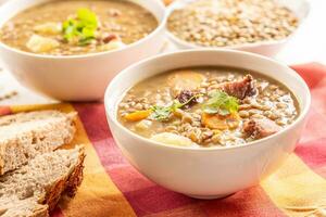 lentilha sopa com peças do defumado carne de porco pescoço, cenouras, batatas e coentro foto