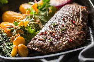 carne flanco bife dentro grade panela com batata purê alho e erva decoração foto