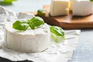 queijo Camembert ou brie queijo com manjericão folhas em mesa foto