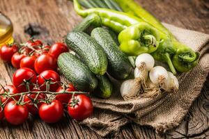 fresco vegetal cebola pepino Pimenta e tomates em rústico carvalho mesa foto