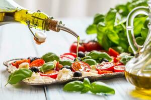 derramando Oliva óleo em caprese salada. saudável italiano ou Mediterrâneo refeição foto