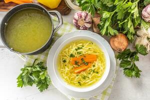 frango sopa caldo dentro uma prato cenoura cebola salsão ervas alho e fresco legumes foto