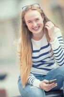 retrato do uma sorridente lindo Adolescência menina com dental aparelho ortodôntico. jovem estudante com escola saco e Móvel telefone foto