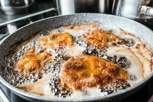 panela com frito Schnitzels dentro fritar óleo. foto