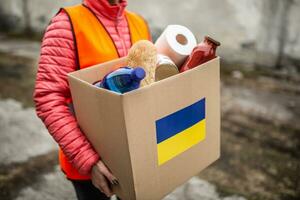 vysne nemecke, Eslováquia. marcha 30. 2022. ngo voluntário carrega uma caixa com básico Comida e banheiro papel com uma ucraniano bandeira adesivo em a cartão foto