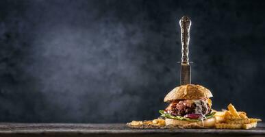 fechar-se casa fez carne hamburguer com faca e fritas em de madeira mesa foto