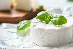 queijo Camembert ou brie queijo com manjericão folhas em mesa foto