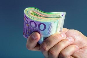 maduro homem segurando uma agrupar do dinheiro dentro dele dedos. euro moeda notas foto