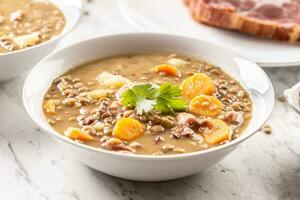 lentilha sopa com peças do defumado carne de porco pescoço, cenouras, batatas e coentro foto