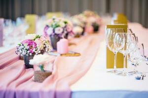 Casamento mesa contexto. lindo mesa conjunto com flores e vidro copos para alguns festivo evento, festa ou Casamento recepção foto