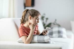 jovem geração sempre em seus telefones representado de uma menina às casa com uma celular dentro dela mão foto