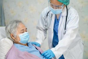 médico usando o estetoscópio para verificar o paciente asiático sênior ou idosa senhora usando uma máscara facial no hospital para proteger a infecção covid-19 coronavírus. foto