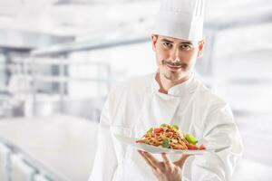 chefe de cozinha dentro restaurante cozinha segurando prato com italiano refeição espaguete foto