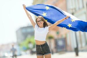 fofa feliz jovem menina com a bandeira do a europeu União dentro a ruas em algum lugar dentro Europa foto