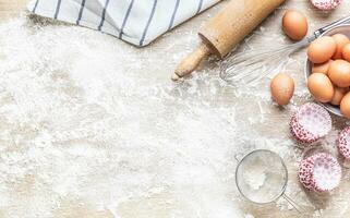 cozimento utensílios com ovos farinha e Bolinho casos em cozinha mesa - topo do Visão foto