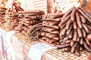 curado carne venda em a mercado com vários defumado salsichas apresentado em uma mesa foto