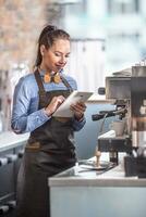 garçonete usa tábua enquanto esperando para expressos para estar acabado dentro uma café criador foto